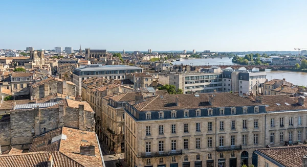 Photographie réelle d'un paysage urbain et architectural de Bordeaux en Gironde montrant les bâtiments caractéristiques de la ville, les toitures variées et le tissu urbain, capturant l'essence du territoire d'intervention de l'entreprise d'étanchéité et de bardage. La photo doit être prise de manière à montrer clairement l'architecture et l'environnement urbain bordelais, distinct d'une simple vue aérienne.