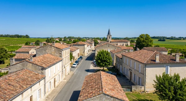 Photographie réelle du centre-bourg de Beychac-et-Caillau en Gironde montrant le patrimoine architectural local, les bâtiments typiques de la commune et l'environnement urbain/rural caractéristique. La photo doit être prise à l'échelle du bâti ou du paysage urbain pour illustrer clairement le siège et la base d'intervention de MGE, distincte des vues urbaines de Bordeaux et Libourne déjà sélectionnées. L'image peut inclure des résidences, des éléments architecturaux locaux ou des voiries caractéristiques du territoire, capturant l'identité visuelle de cette commune de Gironde.